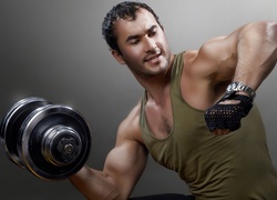 Mężczyzna z ciężarkiem gimnastycznym ćwiczy bicepsy