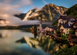 Miasteczko Hallstatt nad zamglonym jeziorem w austriackich Alpach