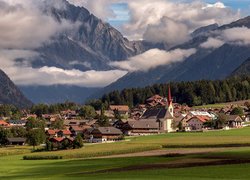 Miasteczko w dolinie na tle mgły nad Dolomitami