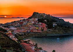 Miasto Castelsardo na Sardynii pod kolorowym niebem zachodzącego słońca