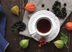 Miechunka rozdęta i gałązki czarnego bzu obok filiżanki z herbatą