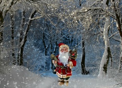 Mikołaj z lampionem i prezentami idzie ścieżką przez zimowy las