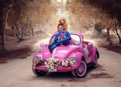 Młoda para pozuje do zdjęcia w różowym Volkswagenie