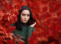Modelka w golfie pośród czerwonych liści jesienią