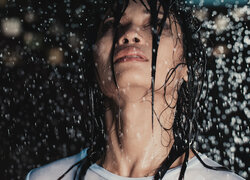 Mokra twarz kobiety w padającym deszczu