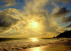 Morska plaża i fale w blasku wschodzącego słońca