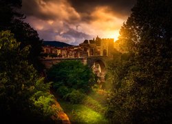 Hiszpania, Miejscowość Besalu, Most Puente de Besalu, Domy, Wzgórza, Drzewa, Roślinność, Wschód słońca, Chmury