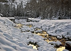 Mostek nad zasypanym śniegiem górskim potokiem