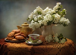 Racuchy na talerzu obok filiżanki z herbatą i bukietu kwiatów w wazonie