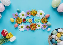 Napis Easter wśród kwiatów w otoczeniu pisanek i tulipanów