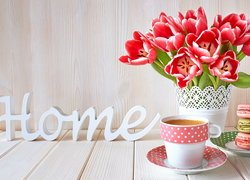 Napis home obok tulipanów i kubka kawy