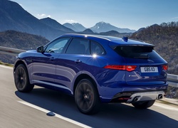 Niebieski Jaguar F-Pace pędzący drogą w górach