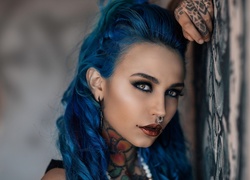 Niebieskowłosa kobieta z kolczykiem w nosie i tatuażami