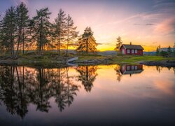 Odbicie czerwonego domu i drzew w jeziorze Vaeleren