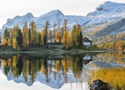 Odbicie jesiennych drzew i domku w jeziorze