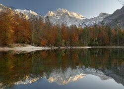 Odbicie jesiennych drzew i ośnieżonych gór w jeziorze