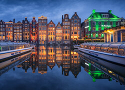 Odbicie w kanale oświetlonych nocą domów w Amsterdamie