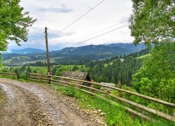 Ogrodzona droga nad domami w dolinie i góry w oddali