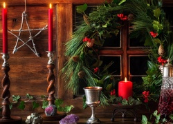 Okno świątecznie przystrojone wiankiem i karafką w blasku świec