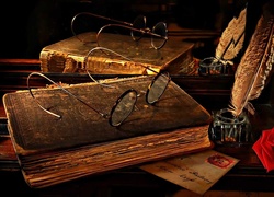 Okulary na książce i kałamarz z piórem odbite w lustrze