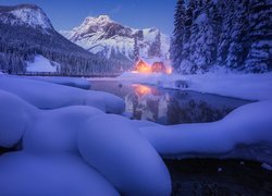 Ośnieżone jezioro Emerald Lake i oświetlony dom na tle gór