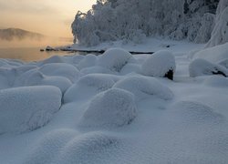 Ośnieżone kamienie i mgła unosząca się nad rzeką