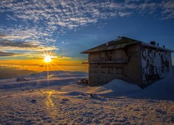 Ośnieżony dom z widokiem na góry Serra da Estrela w promieniach zachodzącego słońca w Portugalii