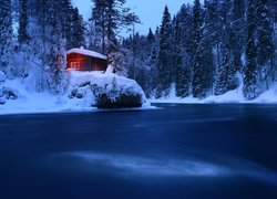 Ośnieżony domek nad rzeką w Parku Narodowym Oulanka