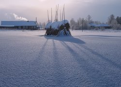 Ośnieżony stóg siana i domy