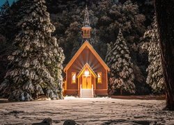 Oświetlona kapliczka pośród ośnieżonych drzew w Parku Narodowym Yosemite