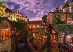 Oświetlone kamienne domy nad kanałem w mieście Mostar