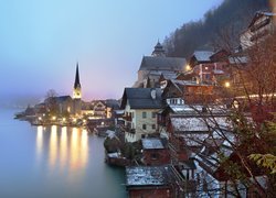 Oświetlone wieczorem miasto Hallstatt w jesiennej mgle