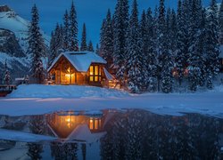 Oświetlony dom w śniegu nad jeziorem Emerald Lake