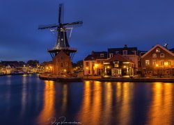 Oświetlony wiatrak i domy nad rzeką Spaarne w Haarlem