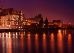 Oświetlony Zamek krzyżacki w Malborku nad rzeką Nogat nocą