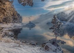 Oszronione kamienie i drzewa nad brzegiem jeziora