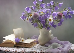 Otwarta książka obok bukietu kwiatów w wazonie