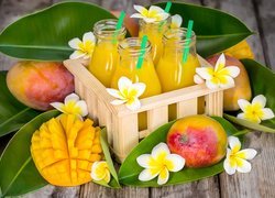 Owoce mango obok skrzynki z butelkami napełnionymi sokiem