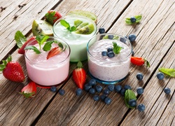 Owocowe koktajle mleczne w szklankach udekorowane jagodami, truskawkami i kiwi