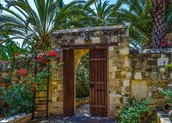 Palmy i kwiaty przy bramie do ogrodu