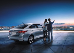 Para stoi przy samochodzie Hyundai Solaris rocznik 2017 oglądając panoramę miasta