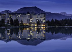 Park Narodowy Banff z oświetlonym hotelem w Lake Louise w Kanadzie nad jeziorem nocą