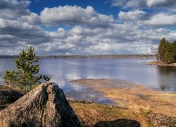 Pierzaste chmury nad drzewami na skałach i jeziorem