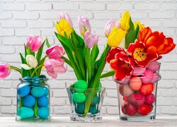 Pisanki i tulipany w szklanych naczyniach