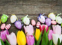Pisanki na deskach nad kolorowymi tulipanami