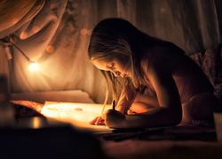 Pisząca dziewczynka w blasku lampy