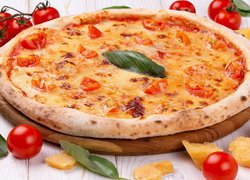 Pizza obok pomidorów na desce