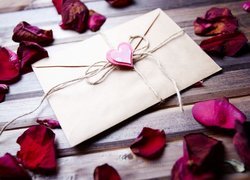 Płatki róży wokół koperty z sercem