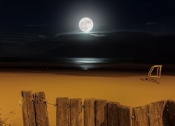 Płot na plaży i księżyc w pełni nad morzem