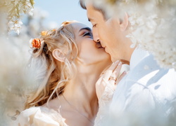 Pocałunek nowożeńców pod kwitnącymi gałązkami